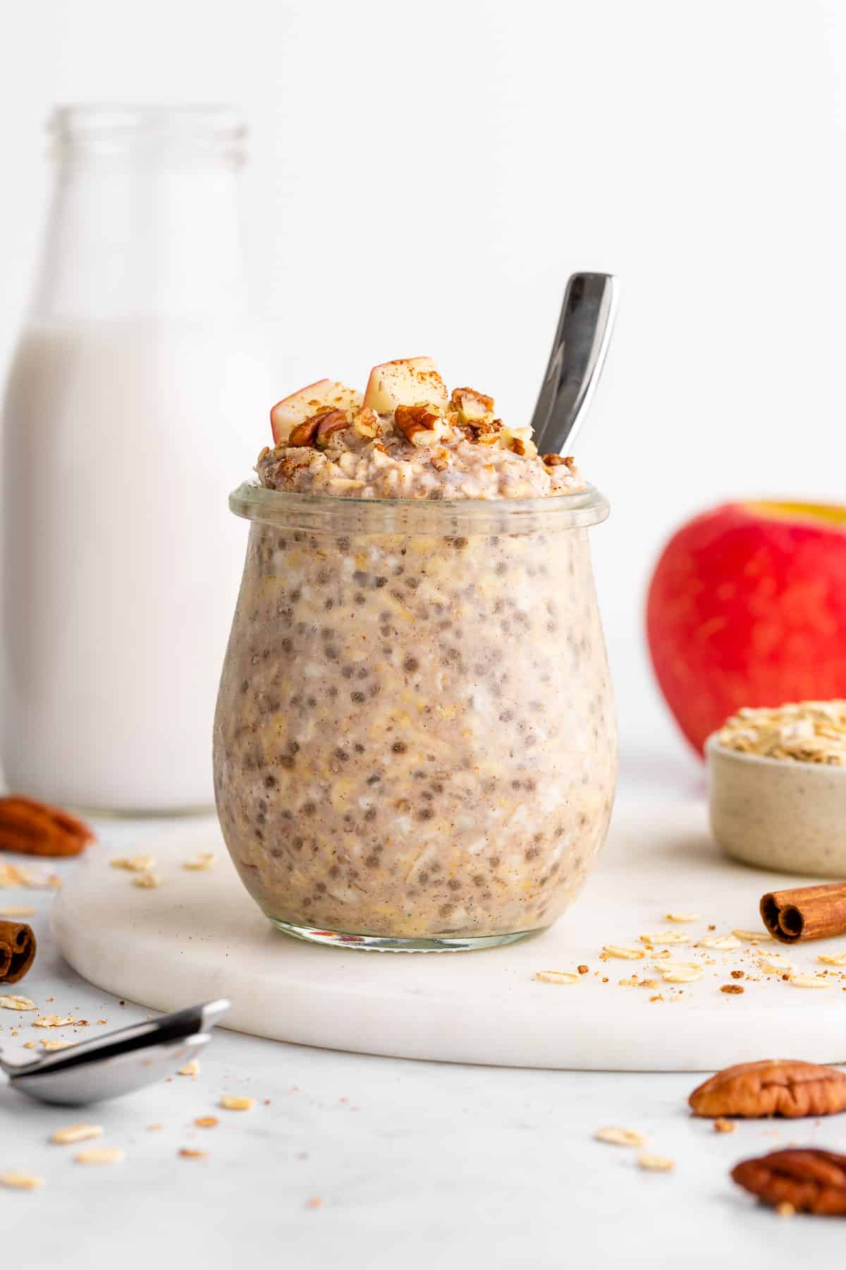 a jar of apple cinnamon overnight oats in a glass jar with chia seeds and yogurt