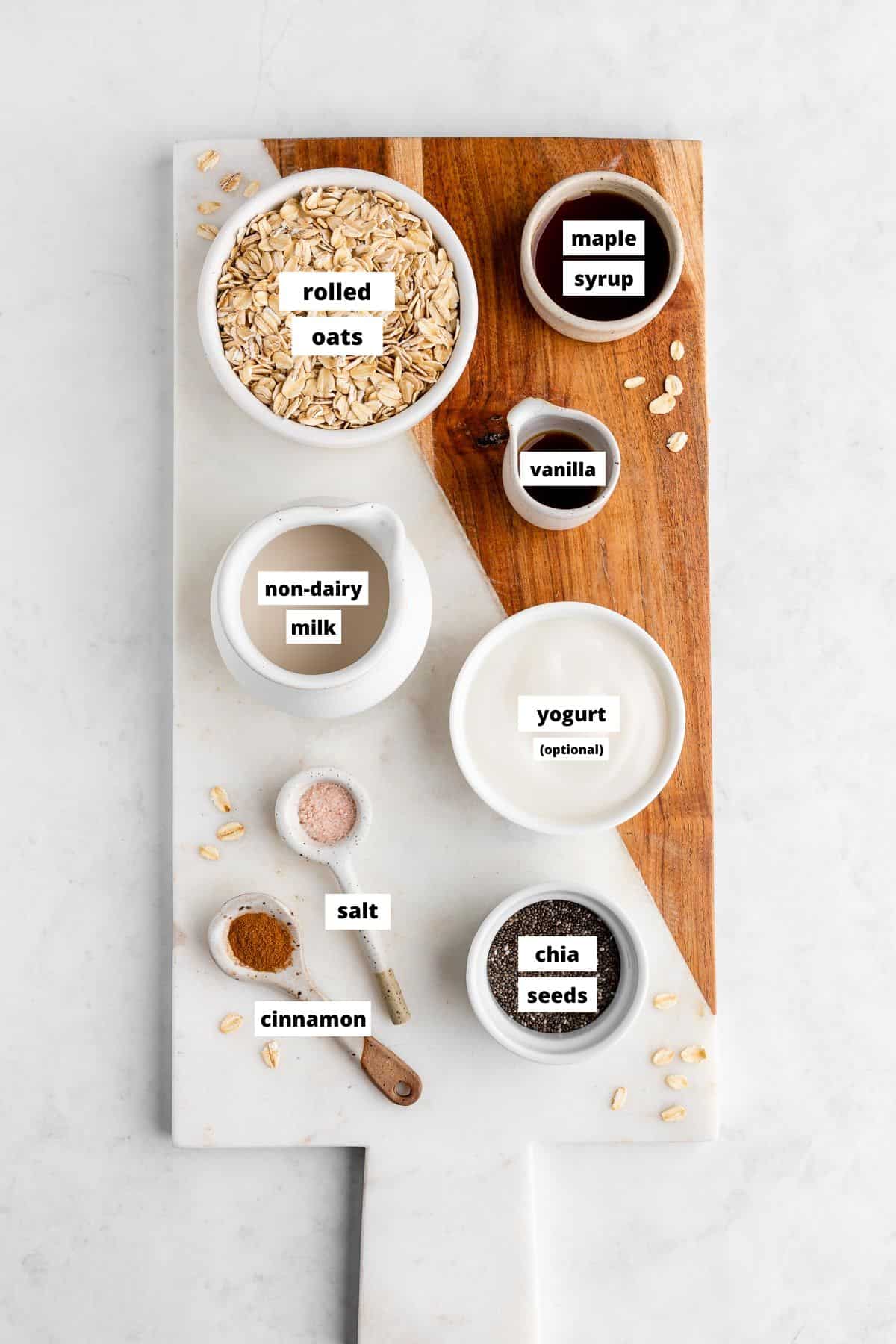 a wooden serving board topped with bowls of basic overnight oats ingredients