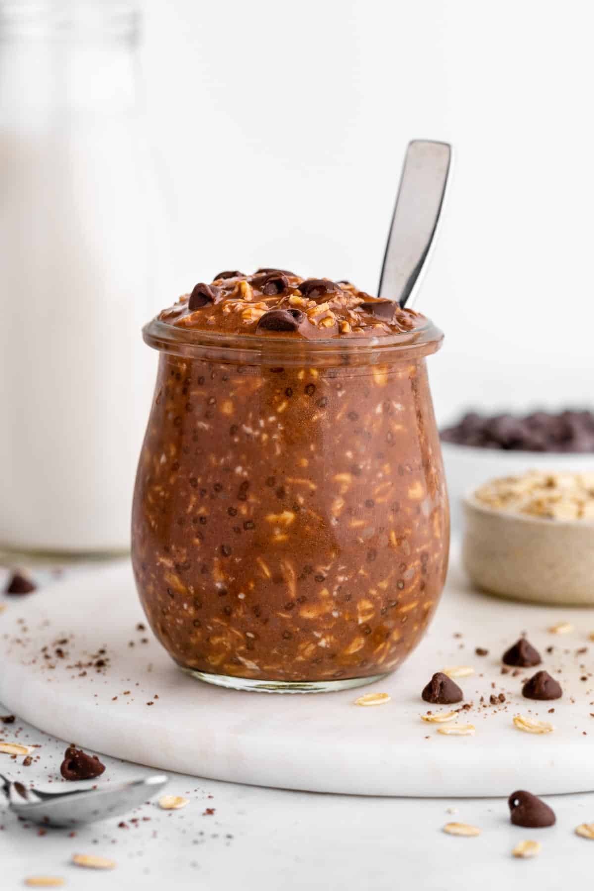 vegan chocolate overnight oats in a jar with a spoon inserted into it