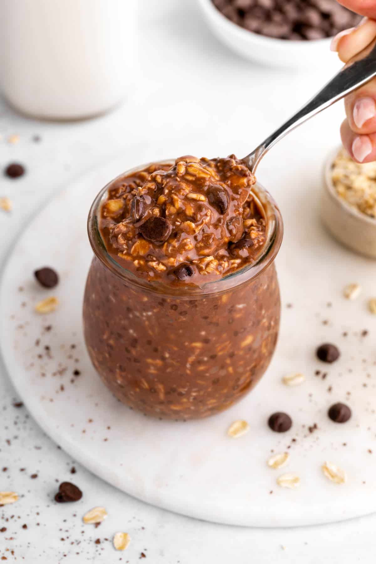 scooping a spoonful of vegan chocolate overnight oats out of a jar