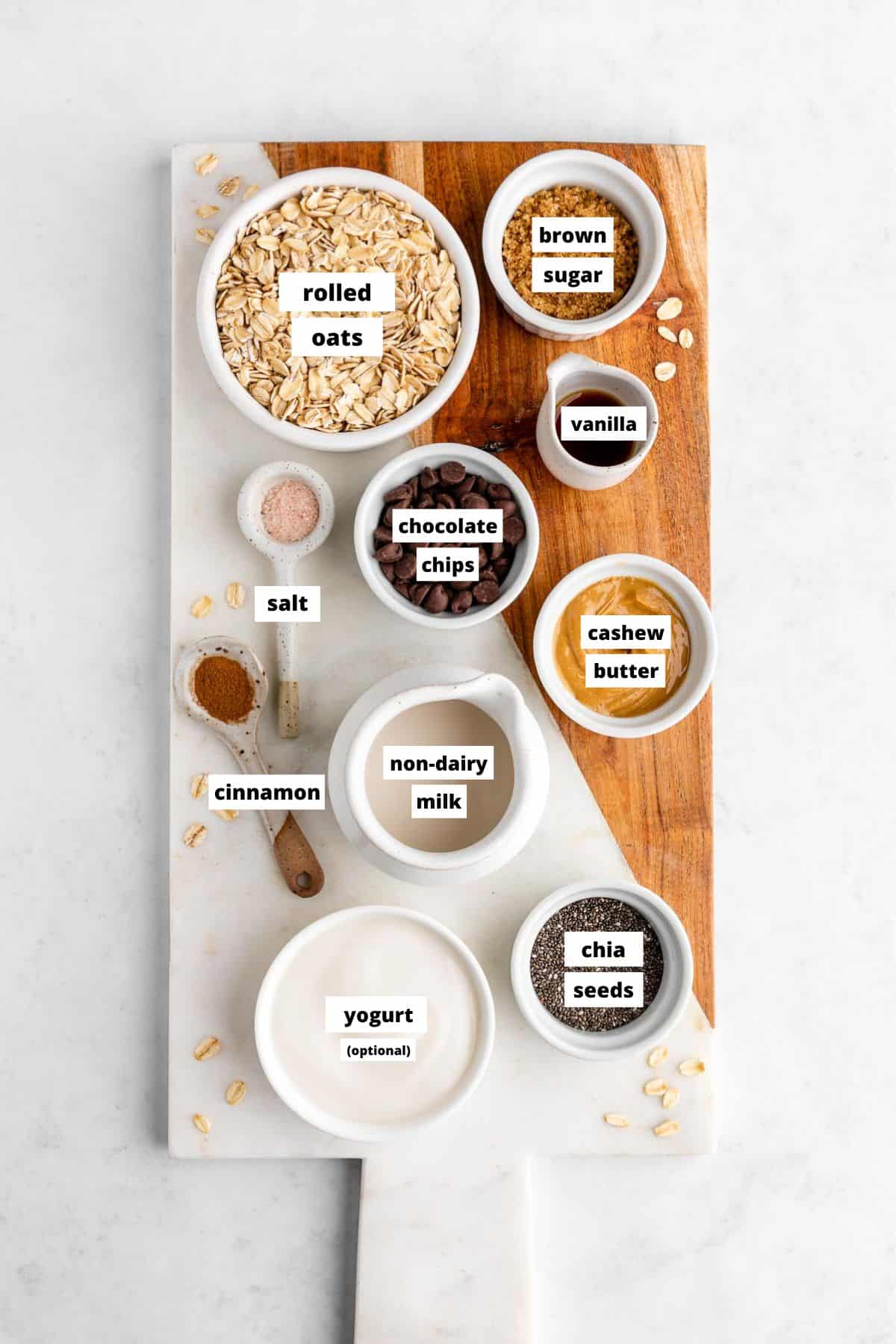 a marble serving board topped with bowls of vegan chocolate chip cookie dough overnight oats ingredients