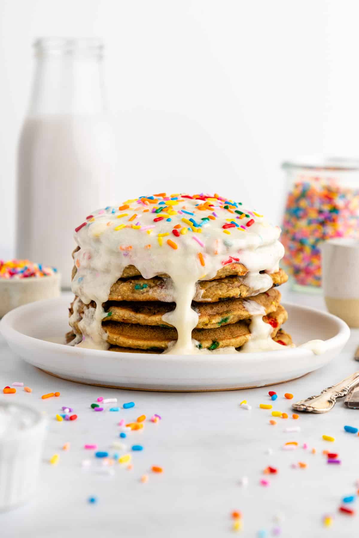 a stack of healthy funfetti pancakes with icing and sprinkles on top