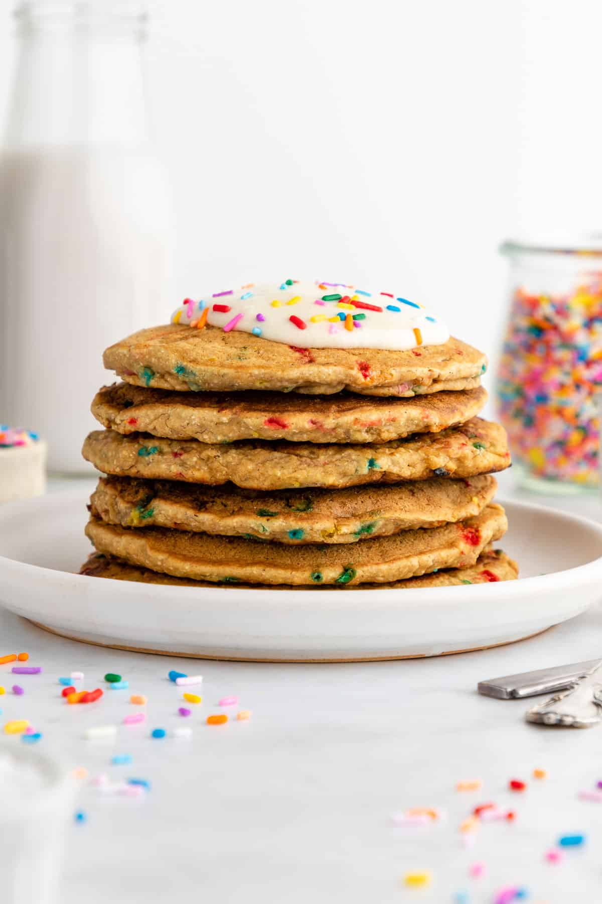 a stack of healthy funfetti pancakes with sprinkles on a white plate