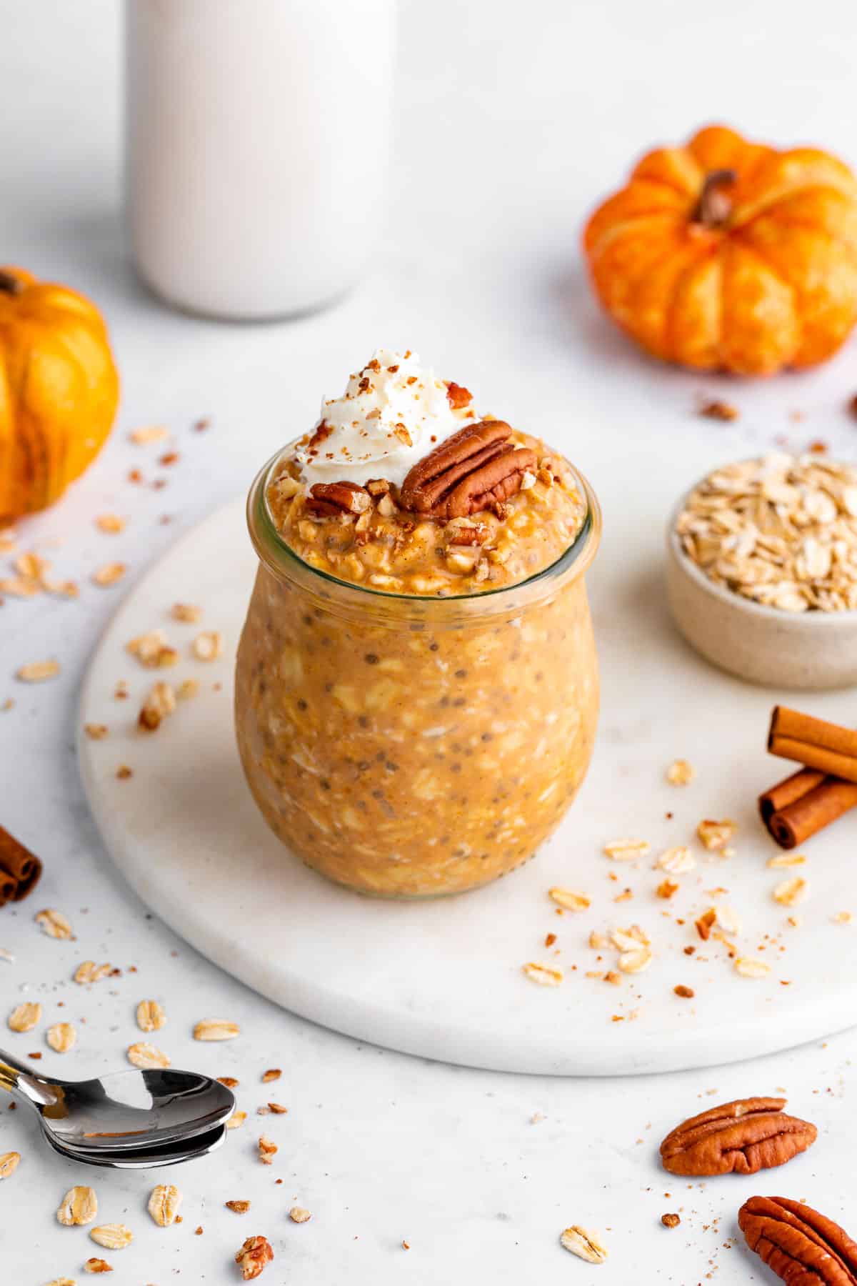 pumpkin pie overnight oats inside a glass jar with whipped cream and pecans on top