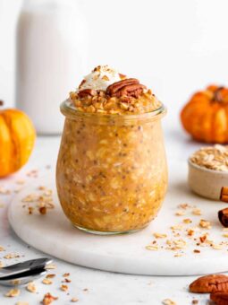 vegan pumpkin pie overnight oats in a jar with whipped cream and pecans