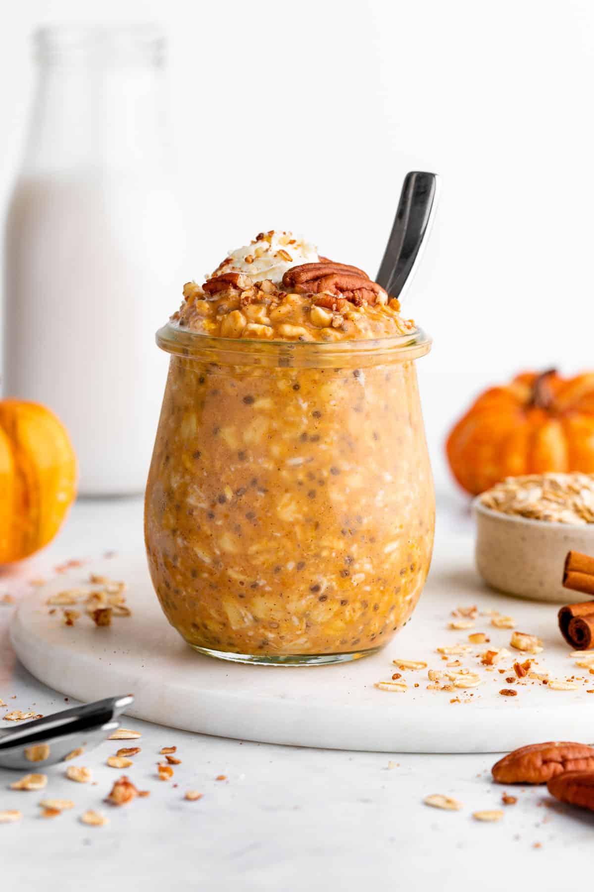 pumpkin pie overnight oats inside a glass jar with chia seeds, yogurt, and pecans