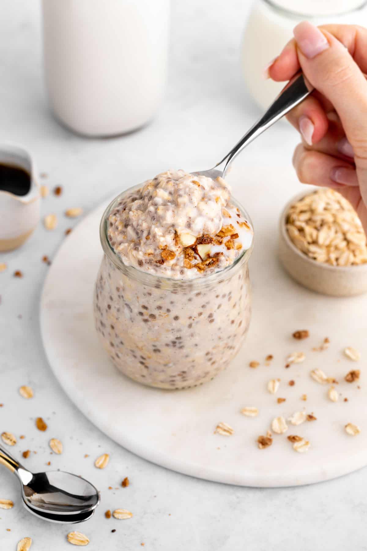 scooping vegan vanilla overnight oats out of a jar with a spoon