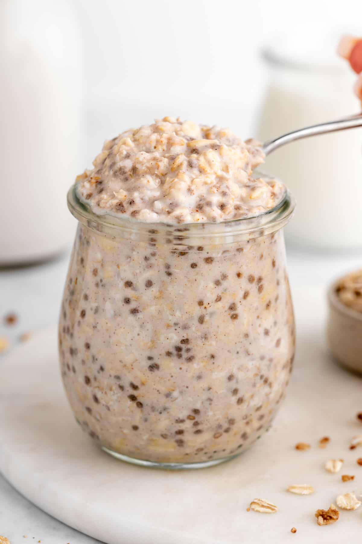 a spoon scooping vegan vanilla overnight oats out of a jar