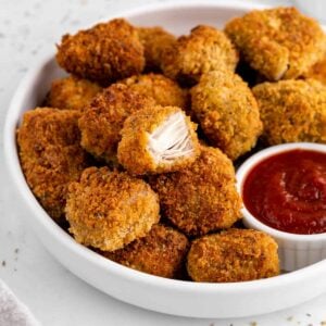 vegan jackfruit nuggets on a white plate with a bite taken out of one of the nuggets