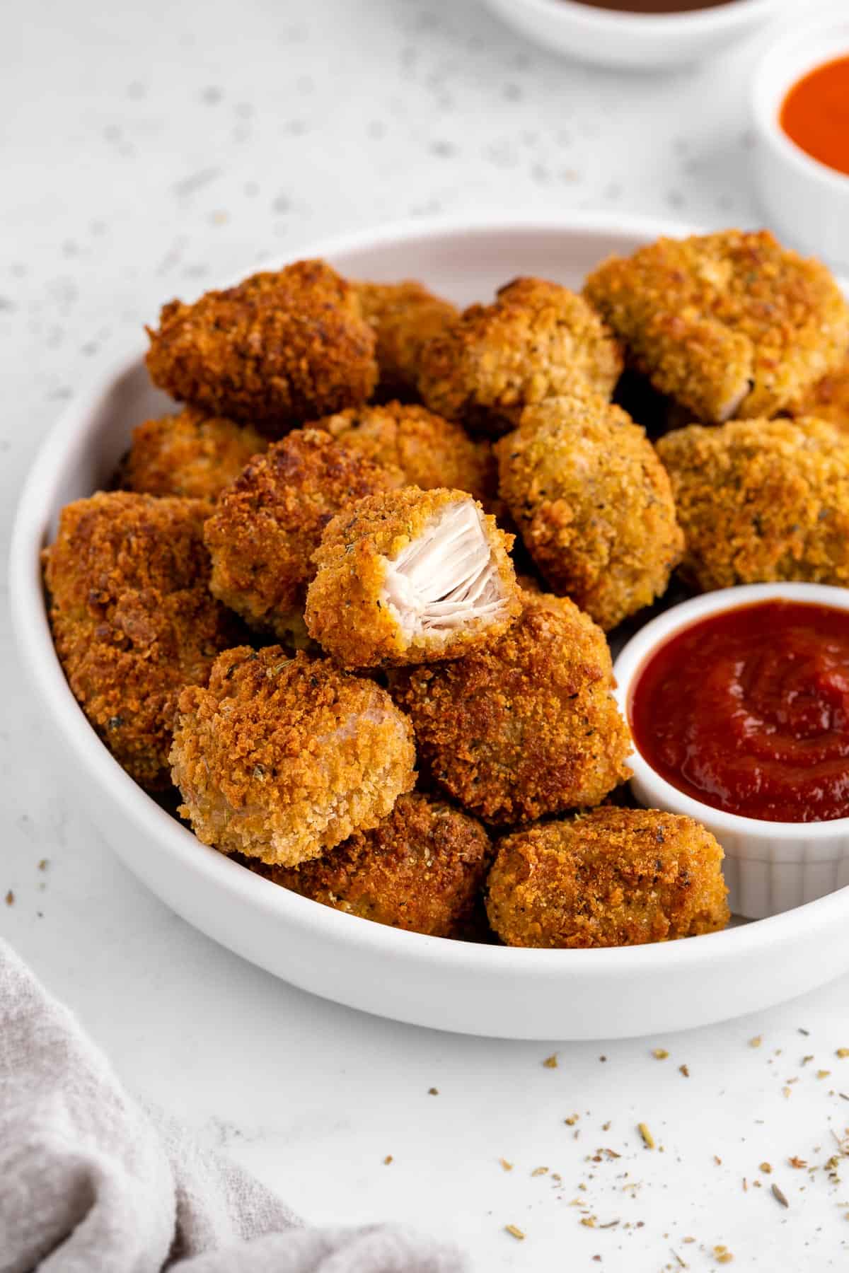 vegan jackfruit nuggets on a white plate with a bite taken out of one of the nuggets