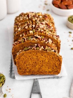 a sliced loaf of vegan pumpkin bread on a wire cooling rack