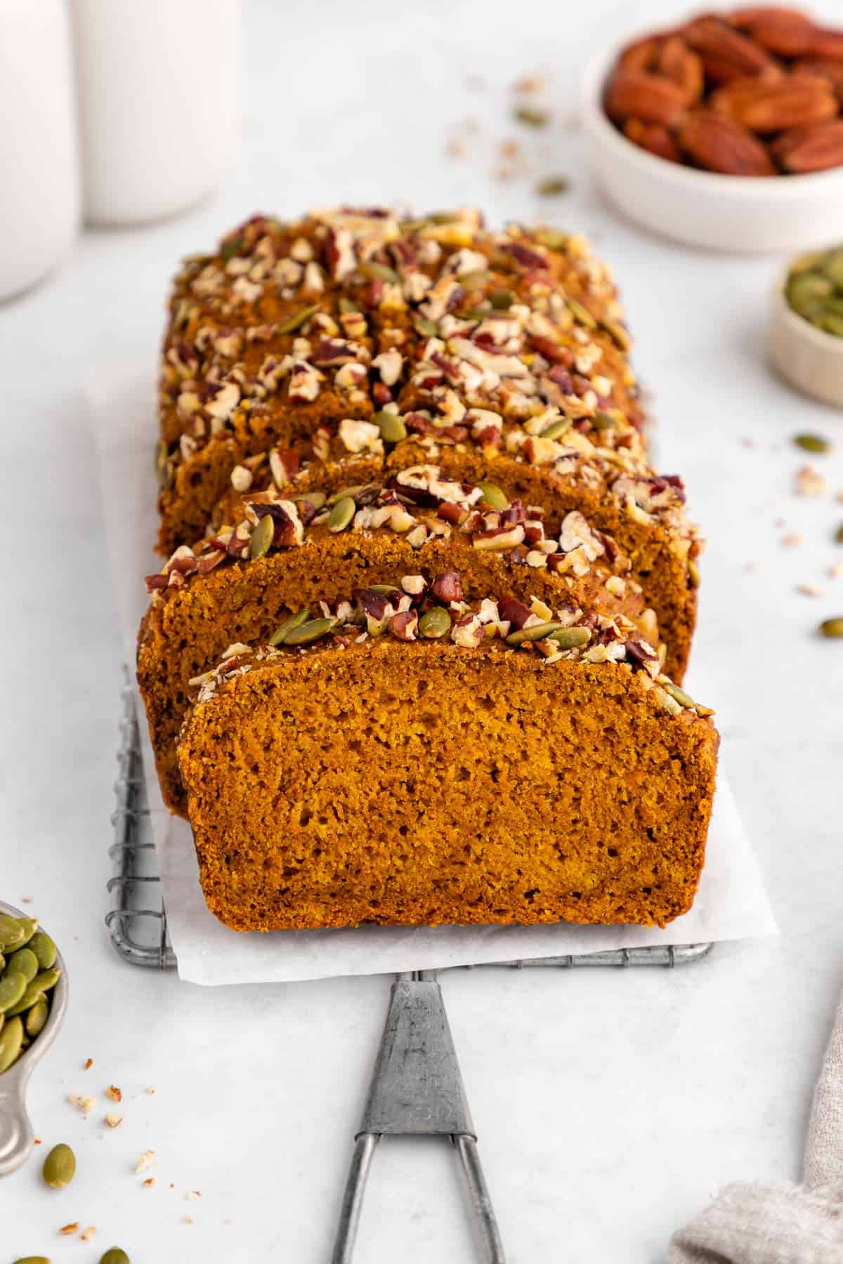 a sliced loaf of vegan pumpkin bread on a wire cooling rack