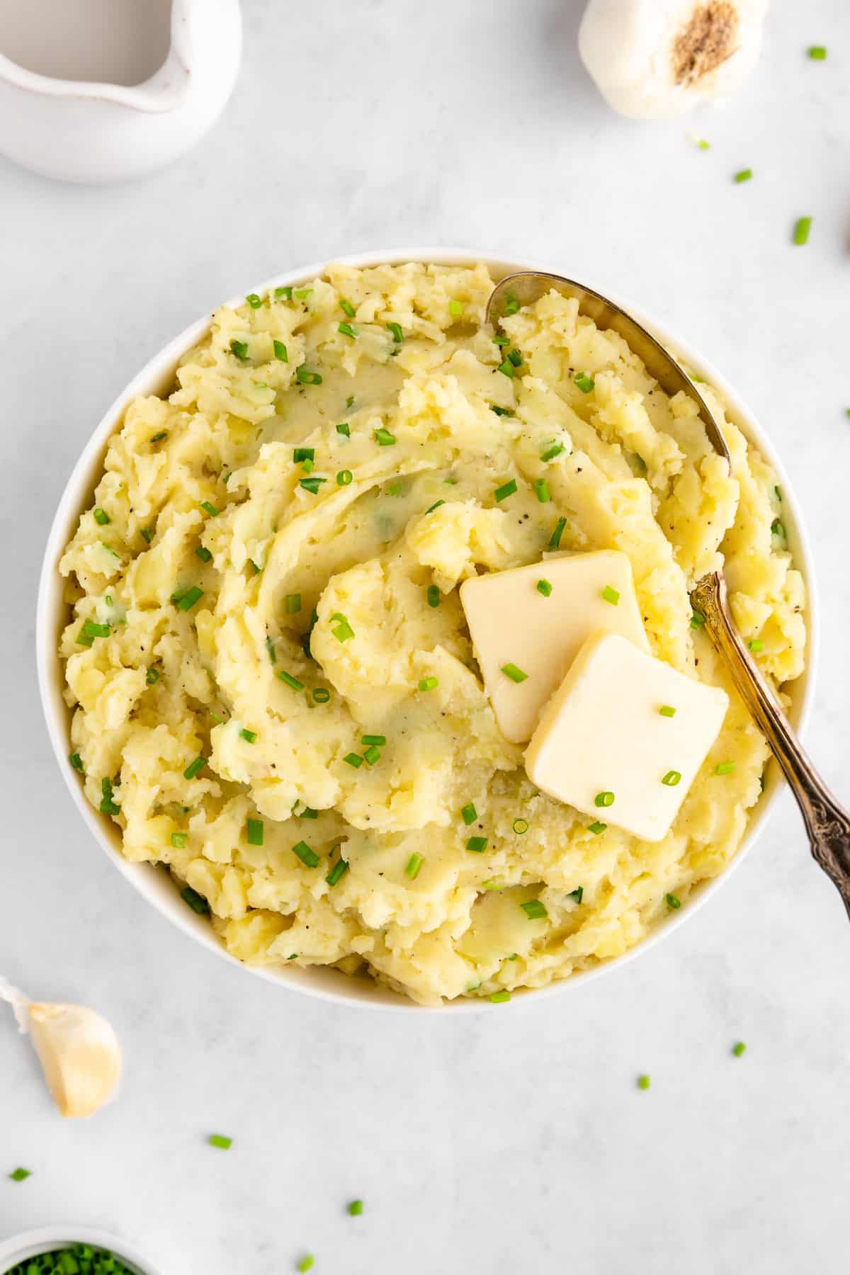a bowl of vegan garlic mashed potatoes with a large serving spoon scooping into it