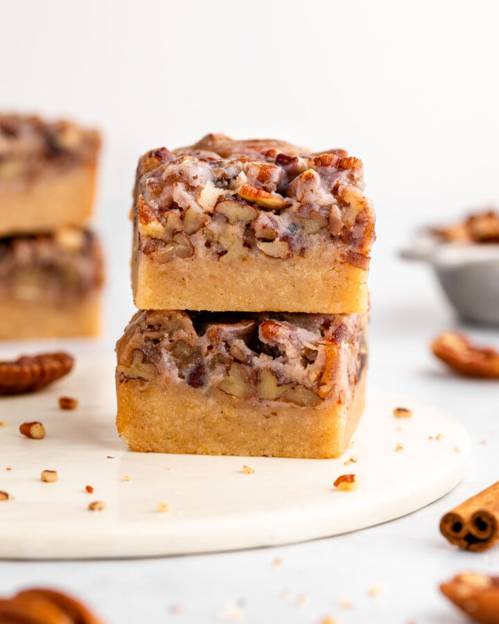 a stack of two vegan pecan pie bars with shortbread crust and sticky pecan topping