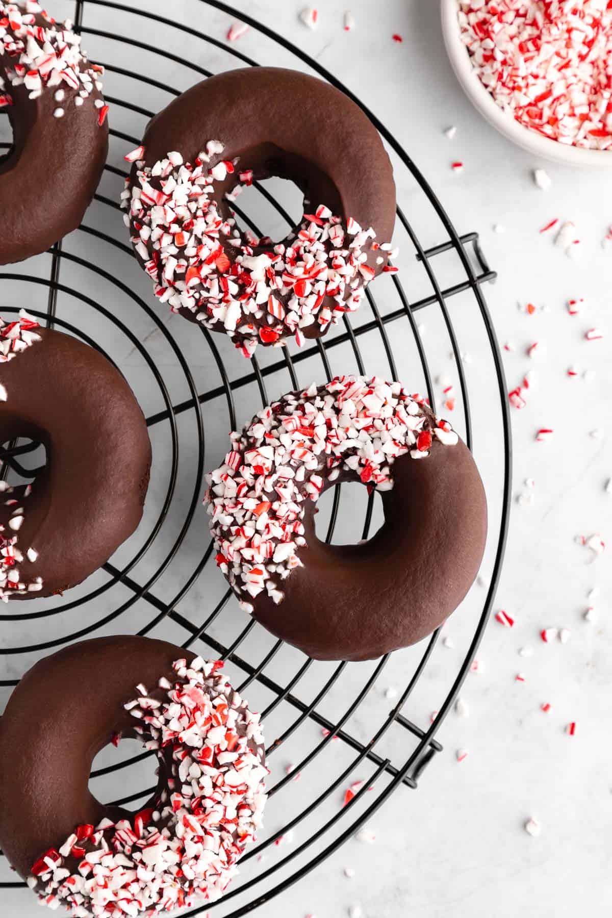 healthy peppermint mocha donuts with crushed candy canes on a black cooling rack