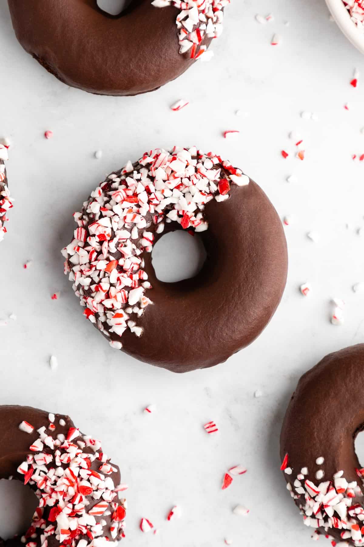 vegan peppermint mocha donuts with chocolate frosting and candy canes on top