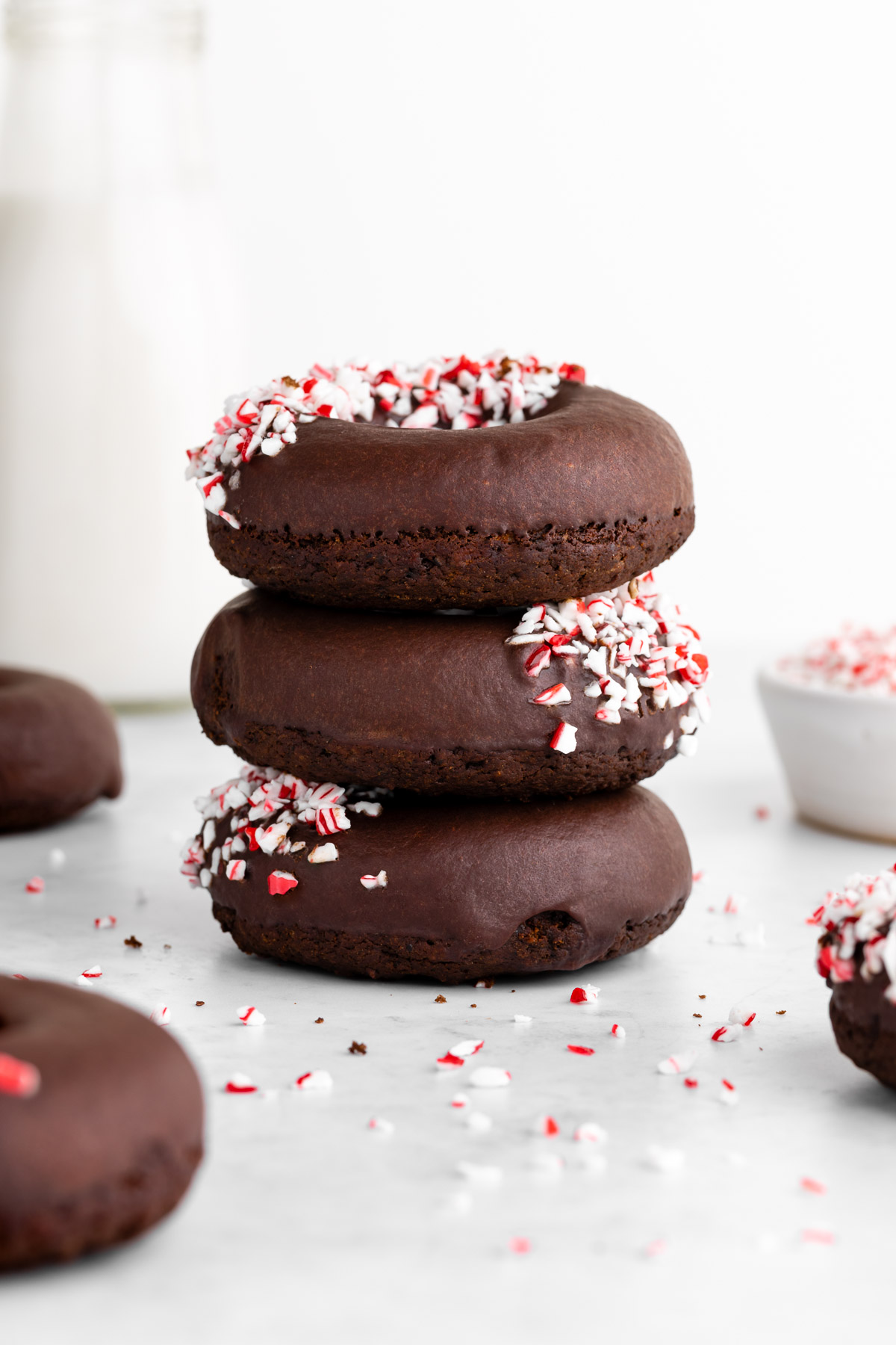 a stack of three vegan peppermint mocha donuts with candy canes on top