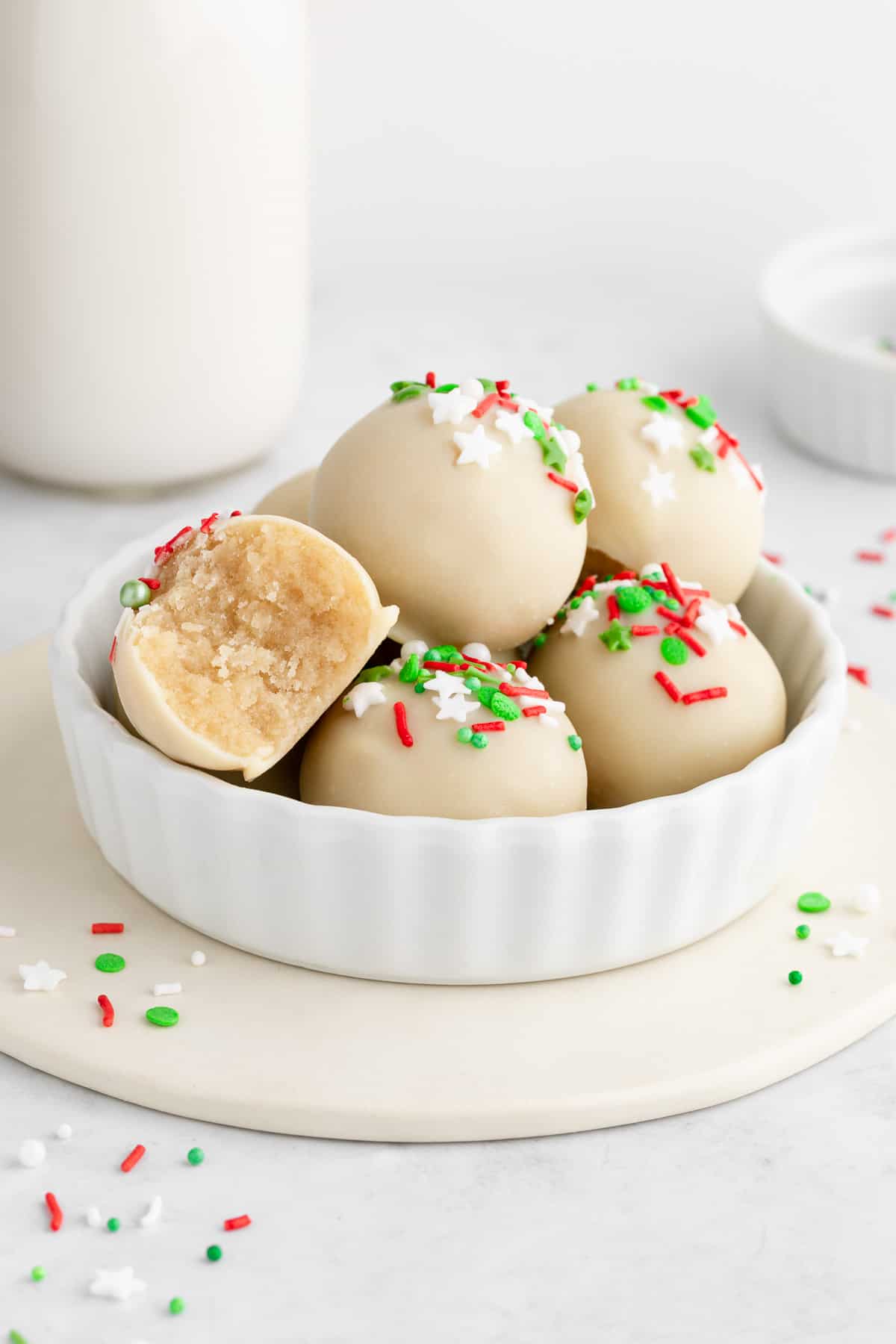 a bowl of Christmas sugar cookie truffles with a bite taken out of one