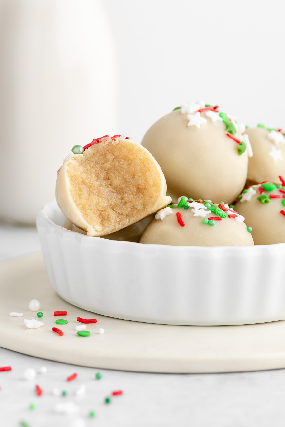 Christmas sugar cookie truffles with white chocolate and sprinkles stacked inside a white bowl