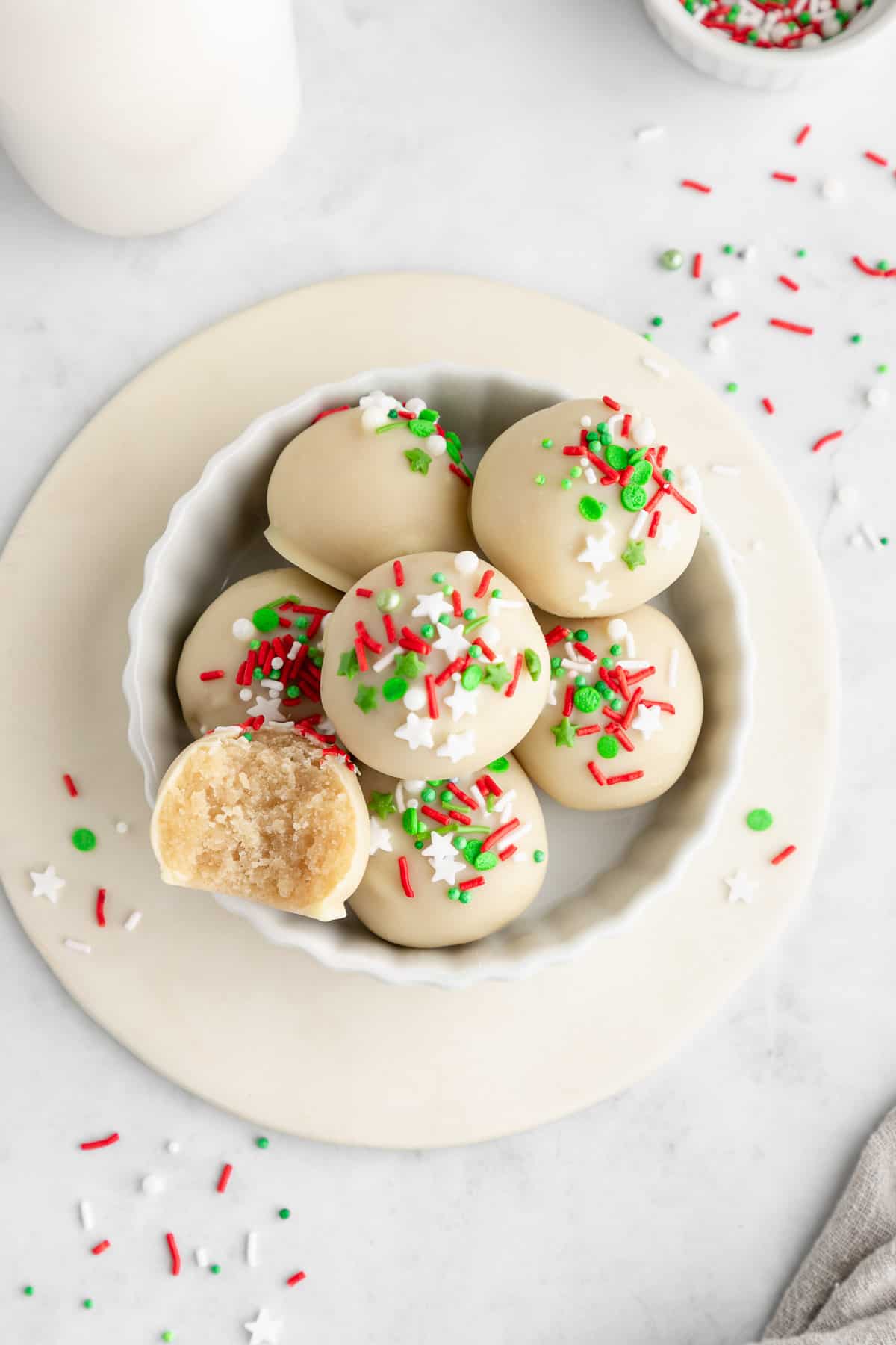 a bowl of sugar cookie truffles with white chocolate and christmas sprinkles