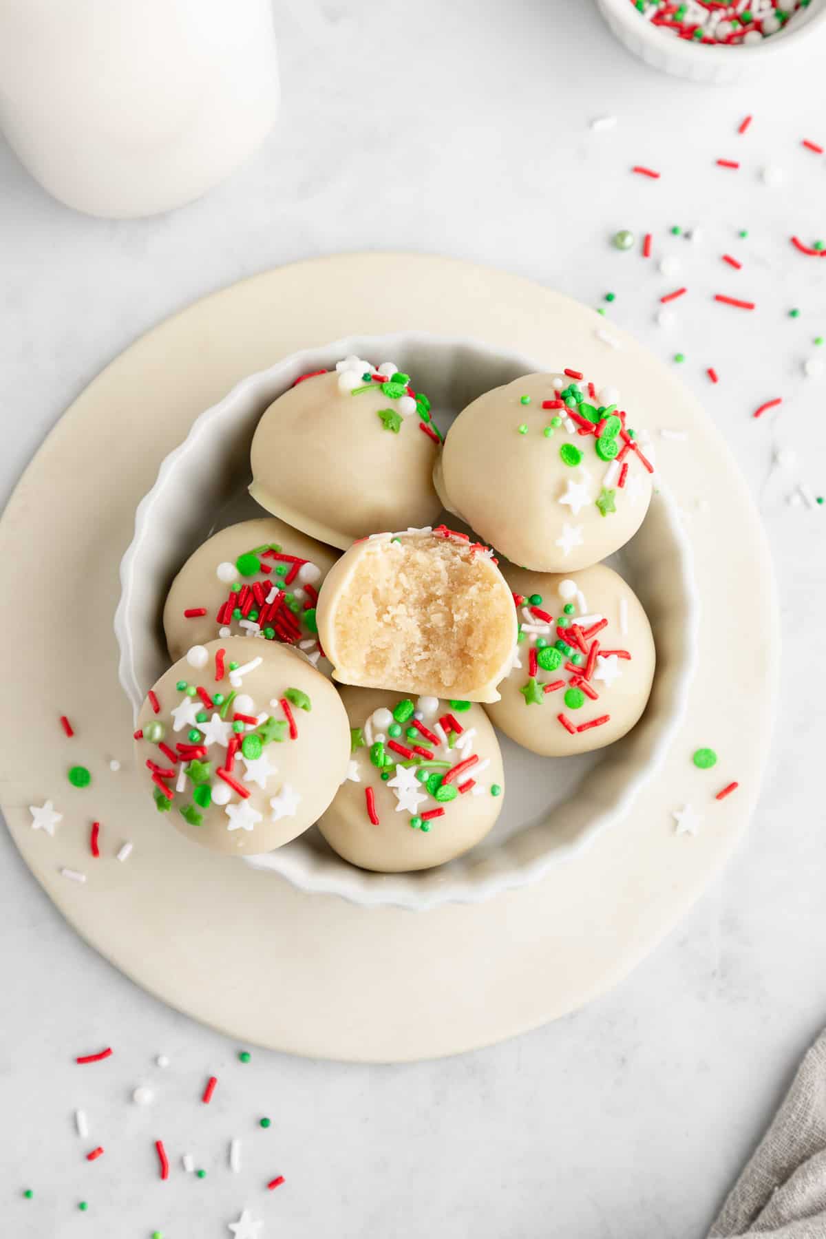 a bowl of Christmas sugar cookie truffles with a bite taken out of the center one