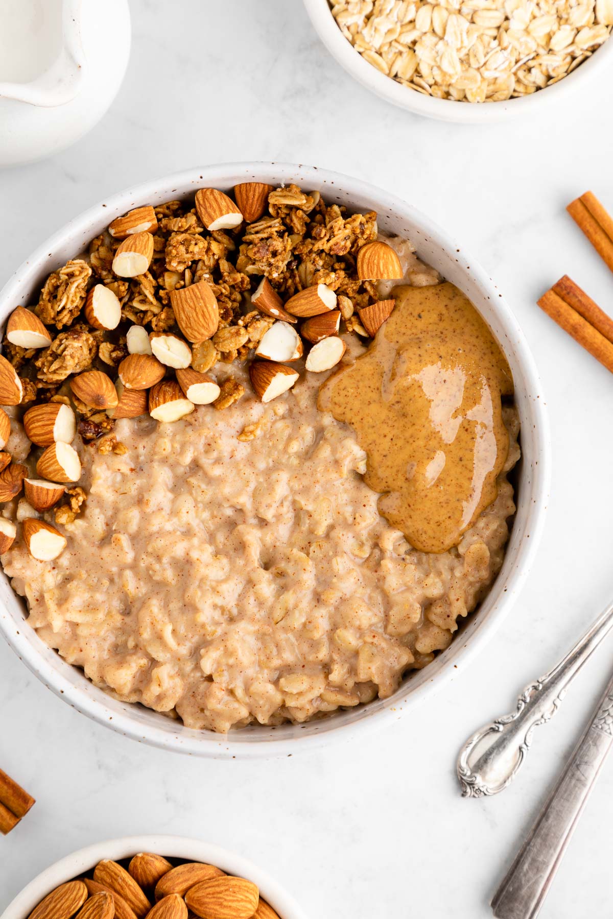 almond butter oatmeal in a bowl with nuts and granola on top