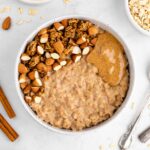 an almond butter oatmeal bowl with granola and almonds on top