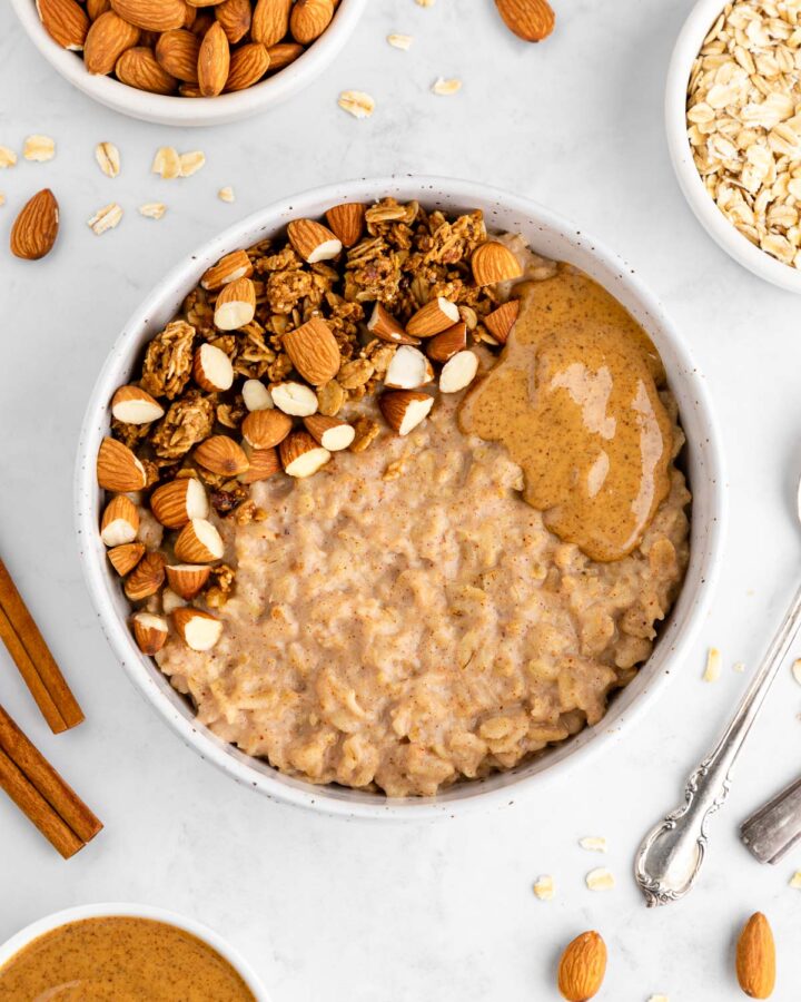 an almond butter oatmeal bowl with granola and almonds on top