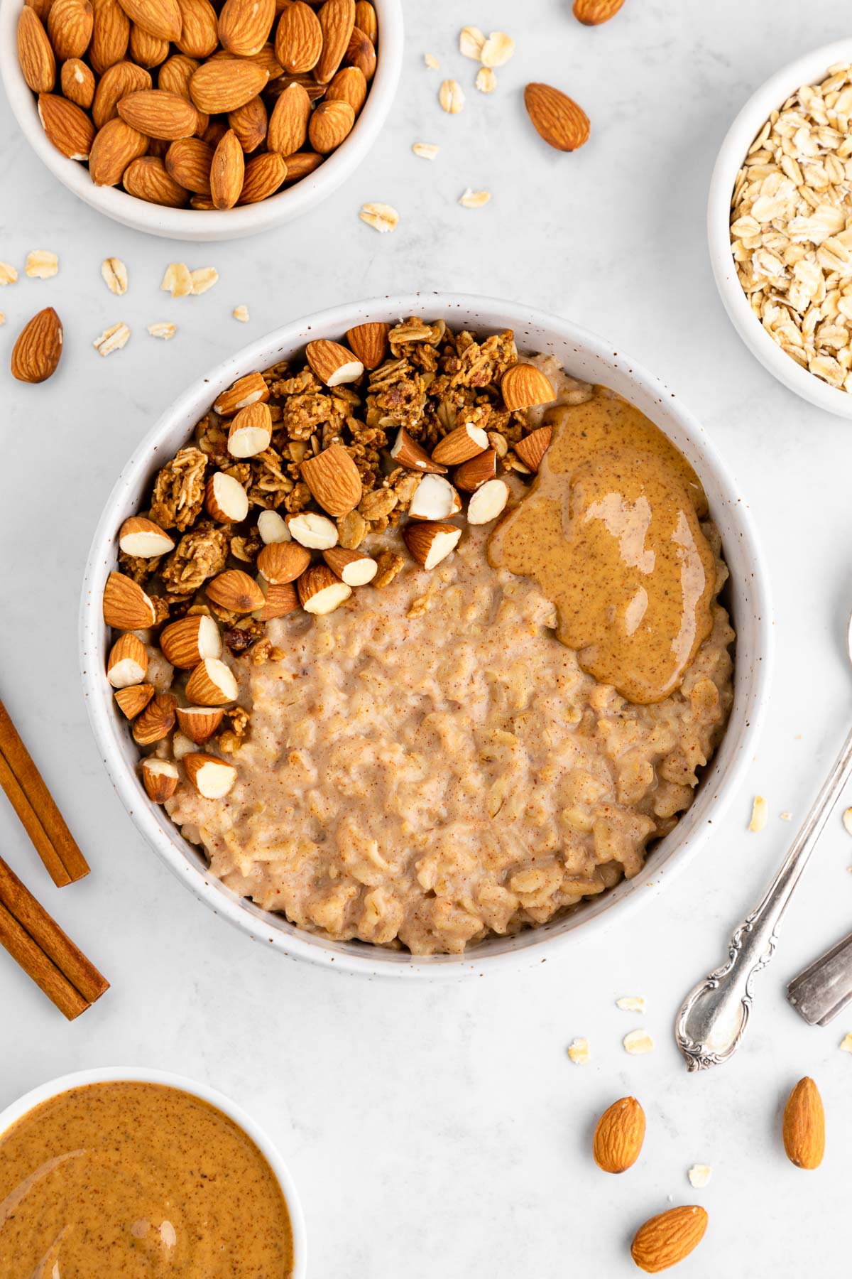 an almond butter oatmeal bowl with granola and almonds on top