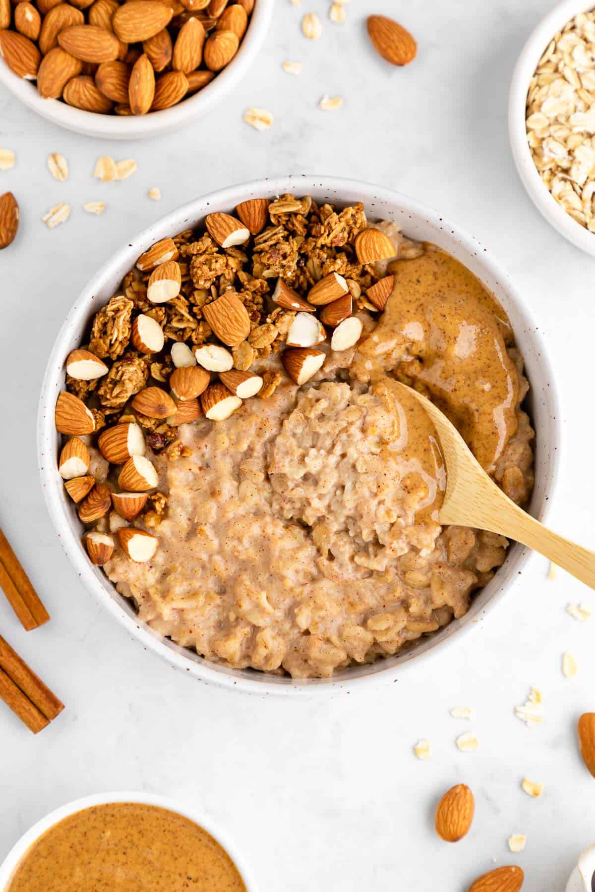 a wooden spoon scooping into a bowl of oatmeal with almond butter