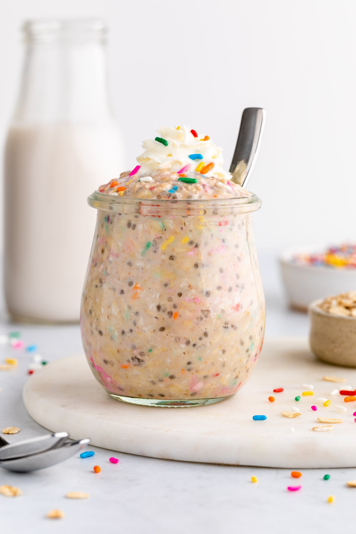 birthday cake overnight oats with sprinkles in a jar and whipped cream on top