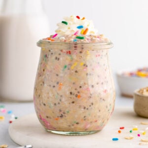 a jar of birthday cake overnight oats with sprinkles and whipped cream
