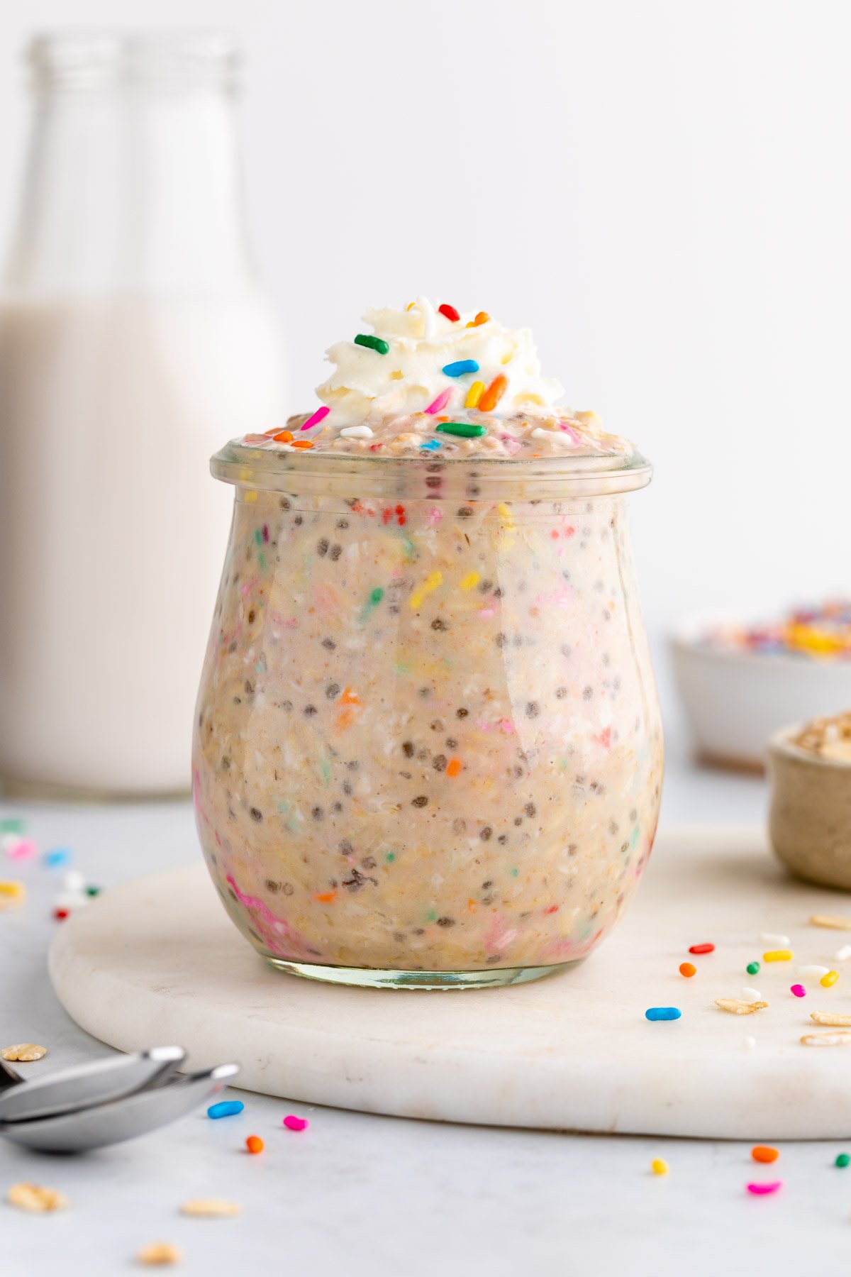 a jar of birthday cake overnight oats with sprinkles and whipped cream