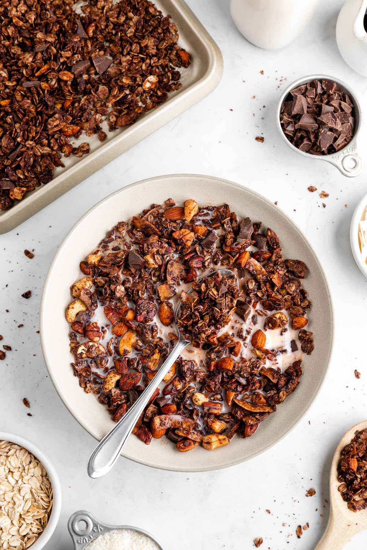 homemade chocolate coconut granola in a ceramic bowl with almond milk and a spoon