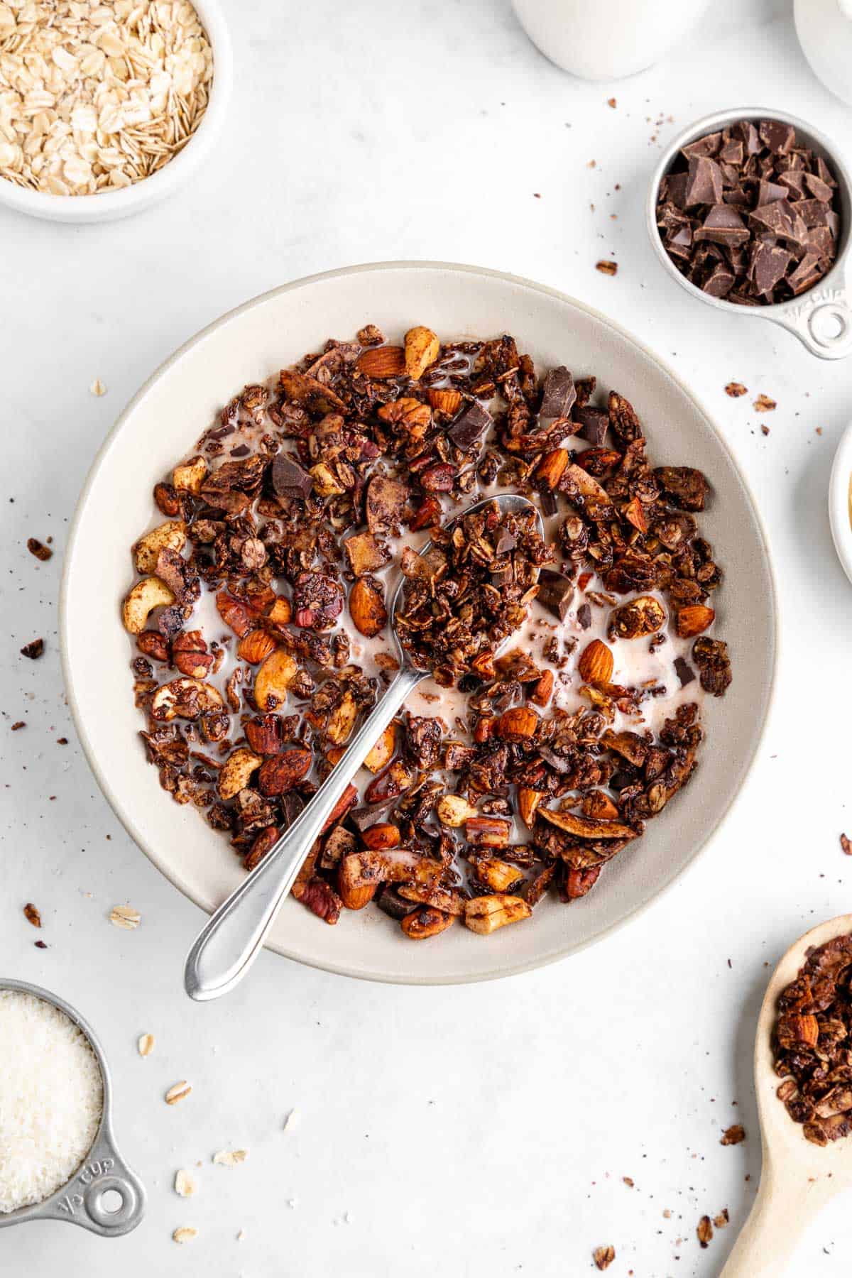a bowl of homemade chocolate coconut granola with almond milk and a spoon