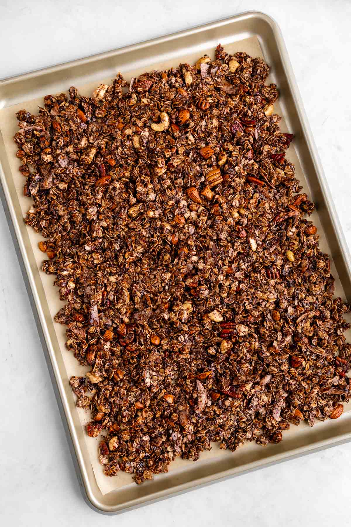 homemade chocolate coconut granola spread on a baking sheet before baking