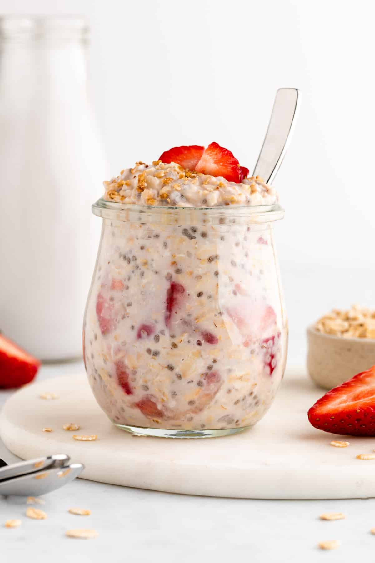strawberries and cream overnight oats in a jar with a spoon