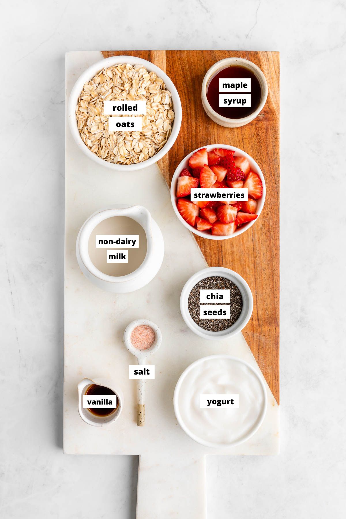 ingredients for strawberries and cream overnight oats on a marble serving board