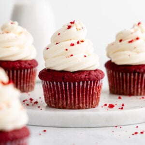 three vegan red velvet cupcakes on a round marble board