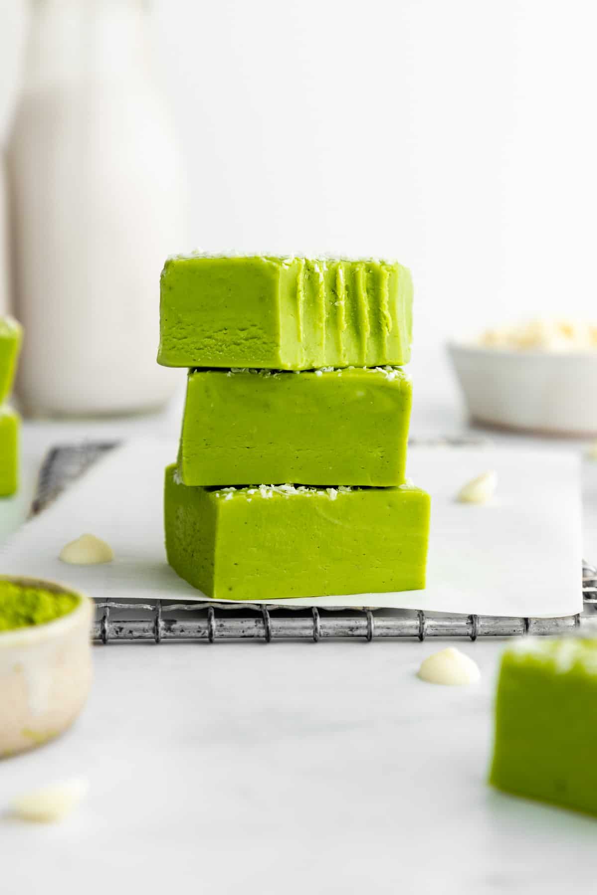 a stack of three white chocolate matcha fudge squares with a bite taken out of the top one