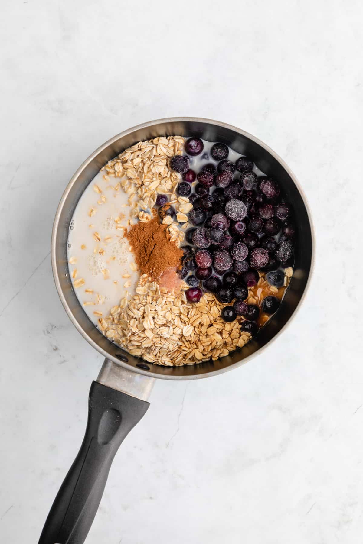 rolled oats, blueberries, almond milk, maple syrup, and cinnamon inside a pot