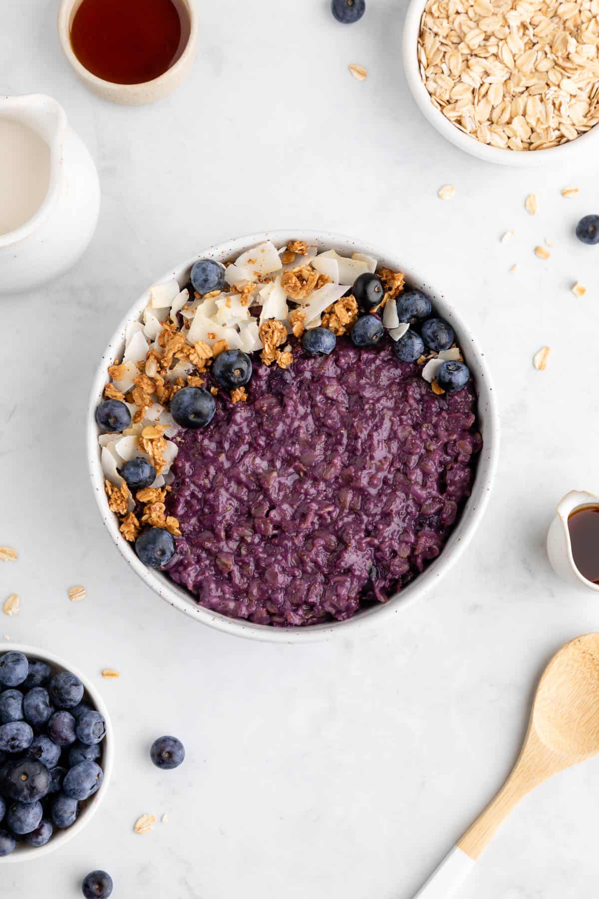 blueberry oatmeal in a ceramic bowl with granola and coconut flakes on top