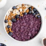 blueberry oatmeal in a ceramic bowl with granola and coconut flakes