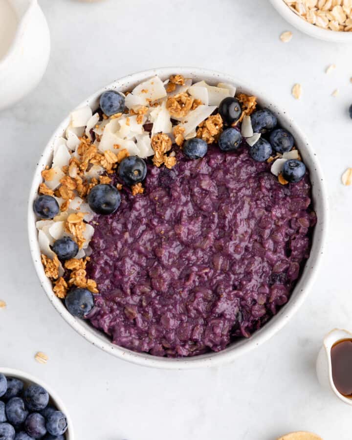 blueberry oatmeal in a ceramic bowl with granola and coconut flakes