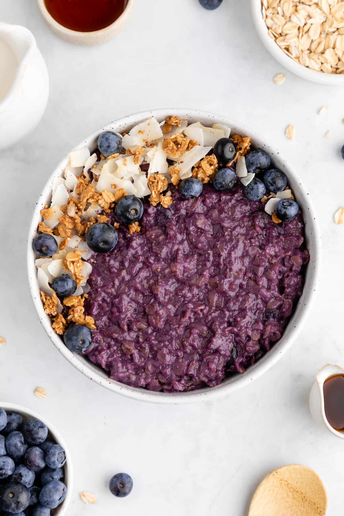 blueberry oatmeal in a ceramic bowl with granola and coconut flakes