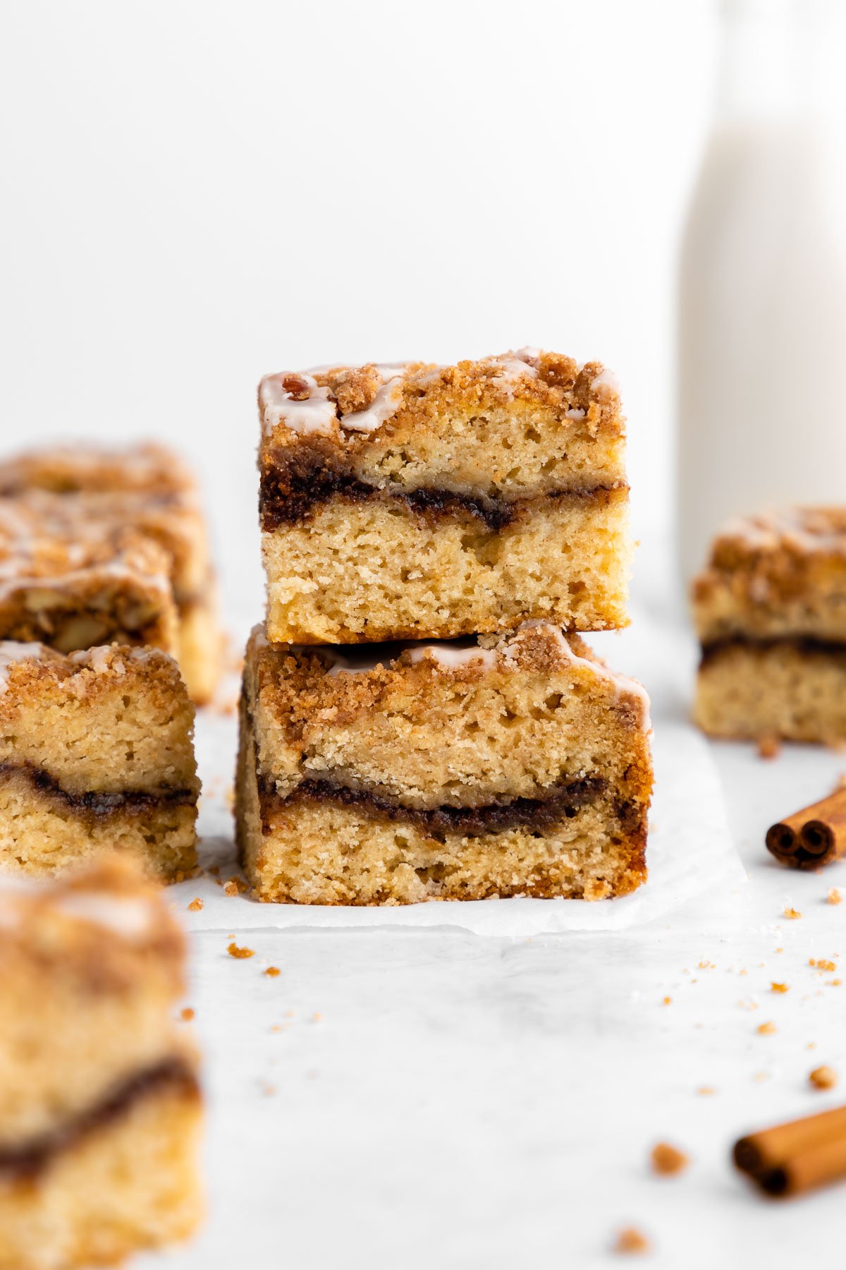 a stack of two slices of vegan cinnamon roll coffee cake with vanilla glaze and cinnamon crumble