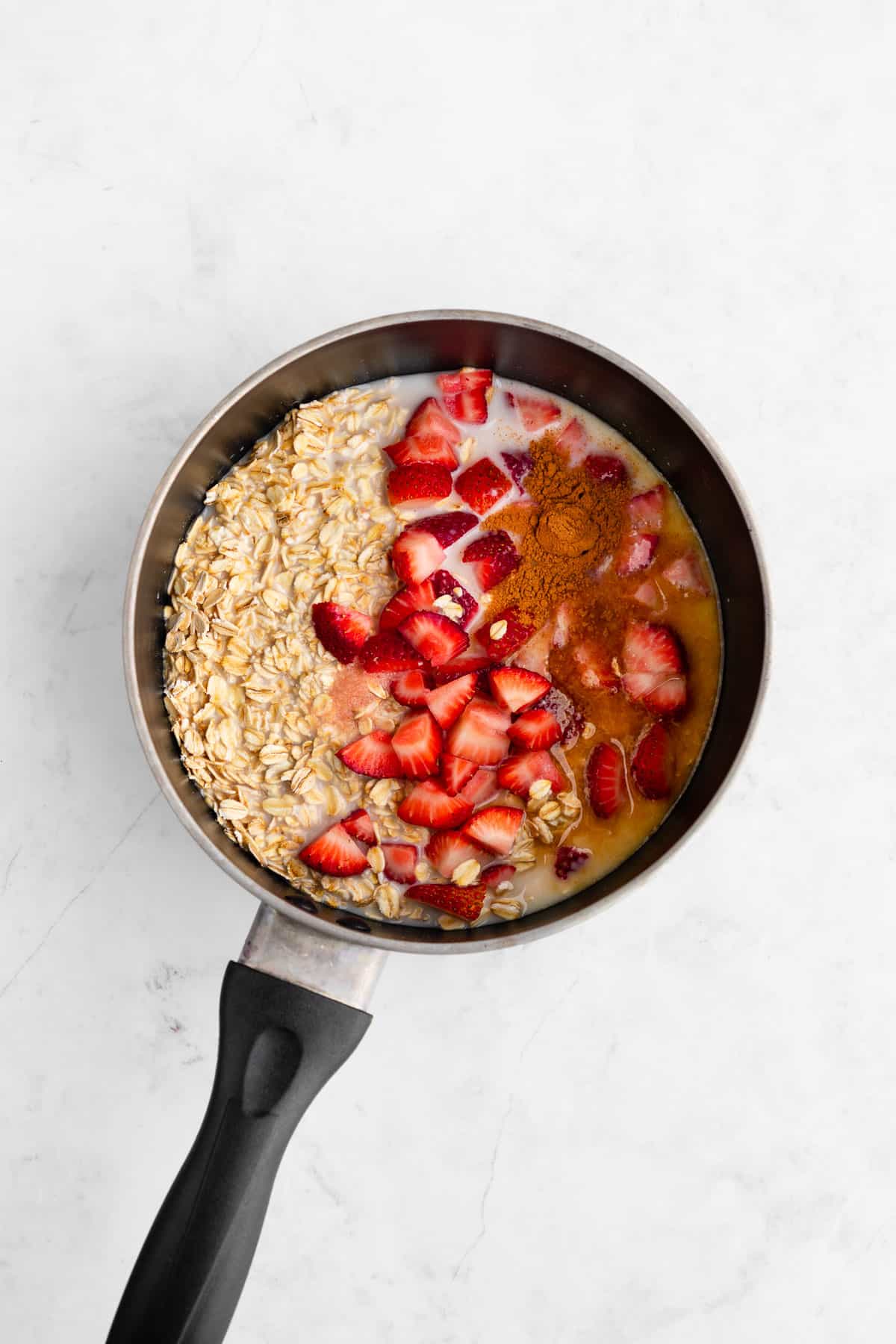 rolled oats, strawberries, almond milk, maple syrup, and cinnamon inside a pot