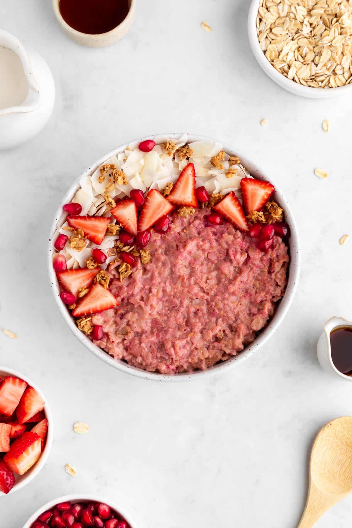 strawberry oatmeal inside a ceramic bowl with granola and coconut flakes on top