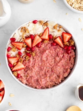 vegan strawberry oatmeal inside a ceramic bowl with granola and coconut flakes on top