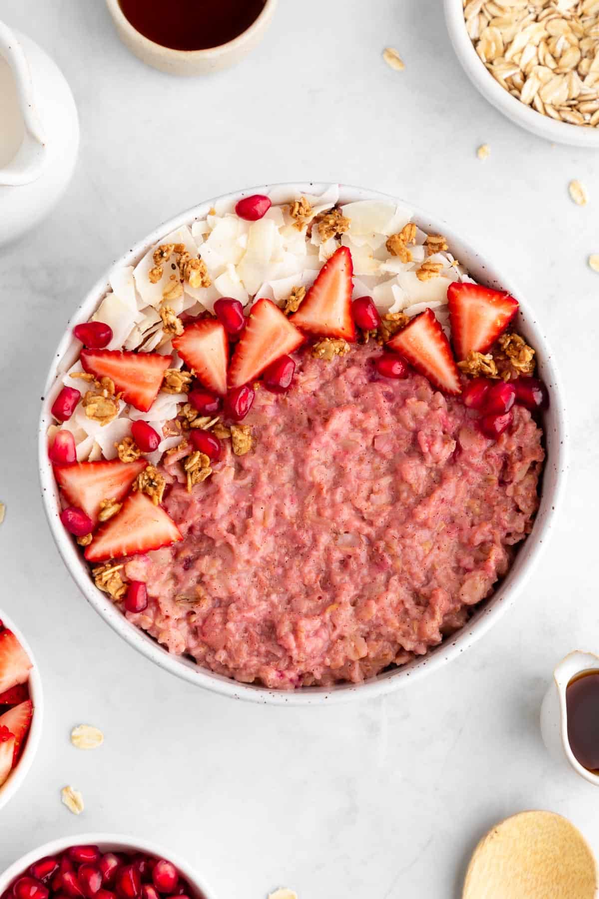 vegan strawberry oatmeal inside a ceramic bowl with granola and coconut flakes on top